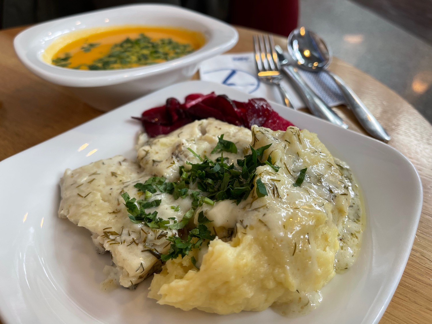 a plate of food with a bowl of soup and spoons