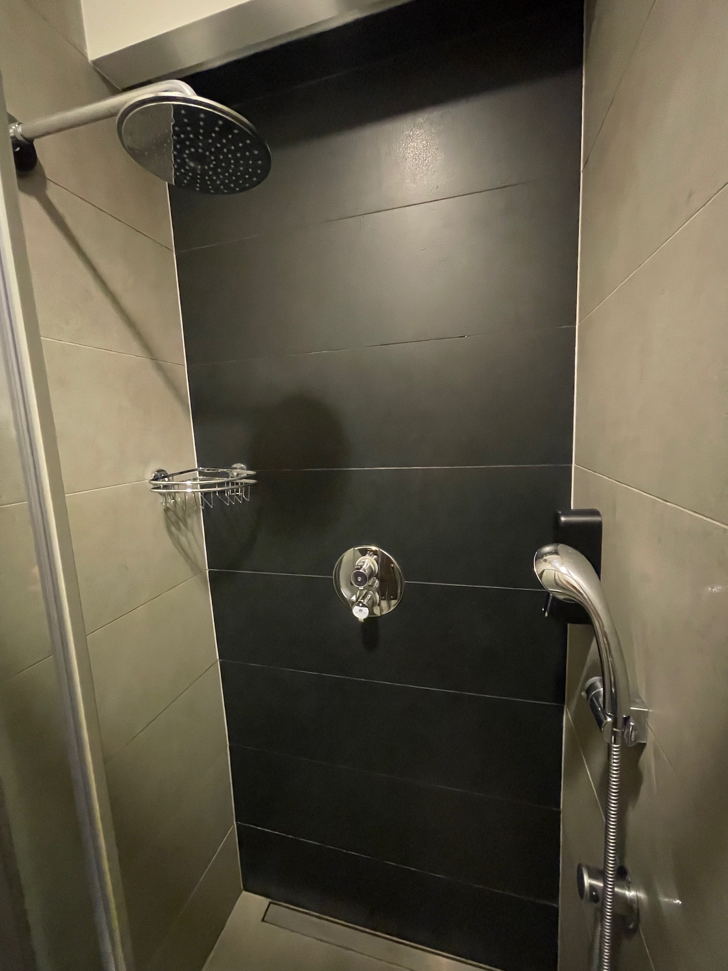 a shower with a black tile wall