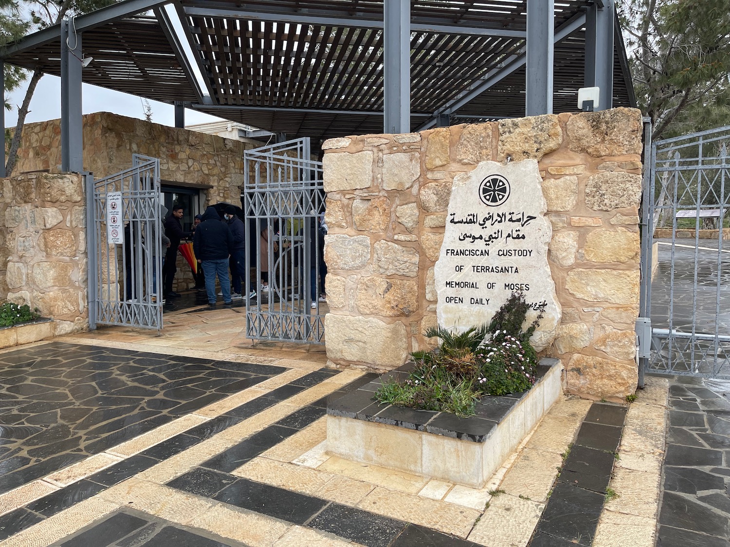 a stone wall with a sign and a stone wall with a stone wall and a stone walkway with a stone wall and a stone wall with a stone wall with a stone wall and a stone wall with