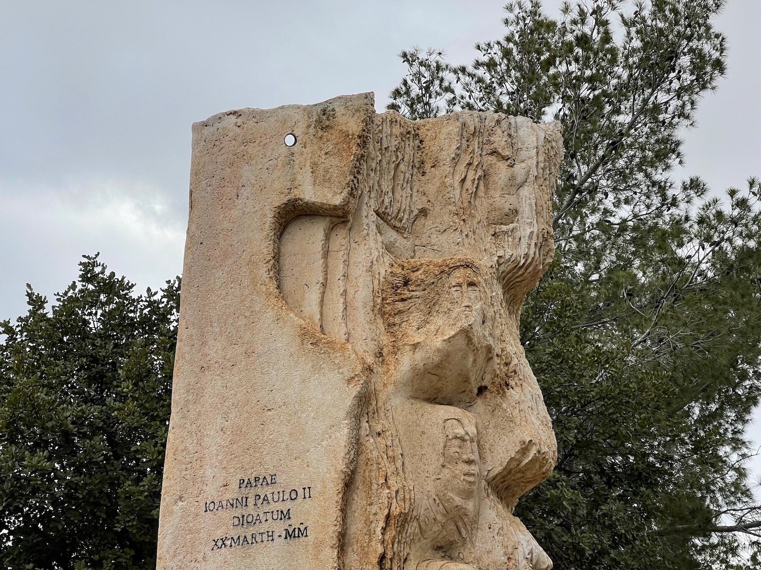 a stone sculpture with trees in the background