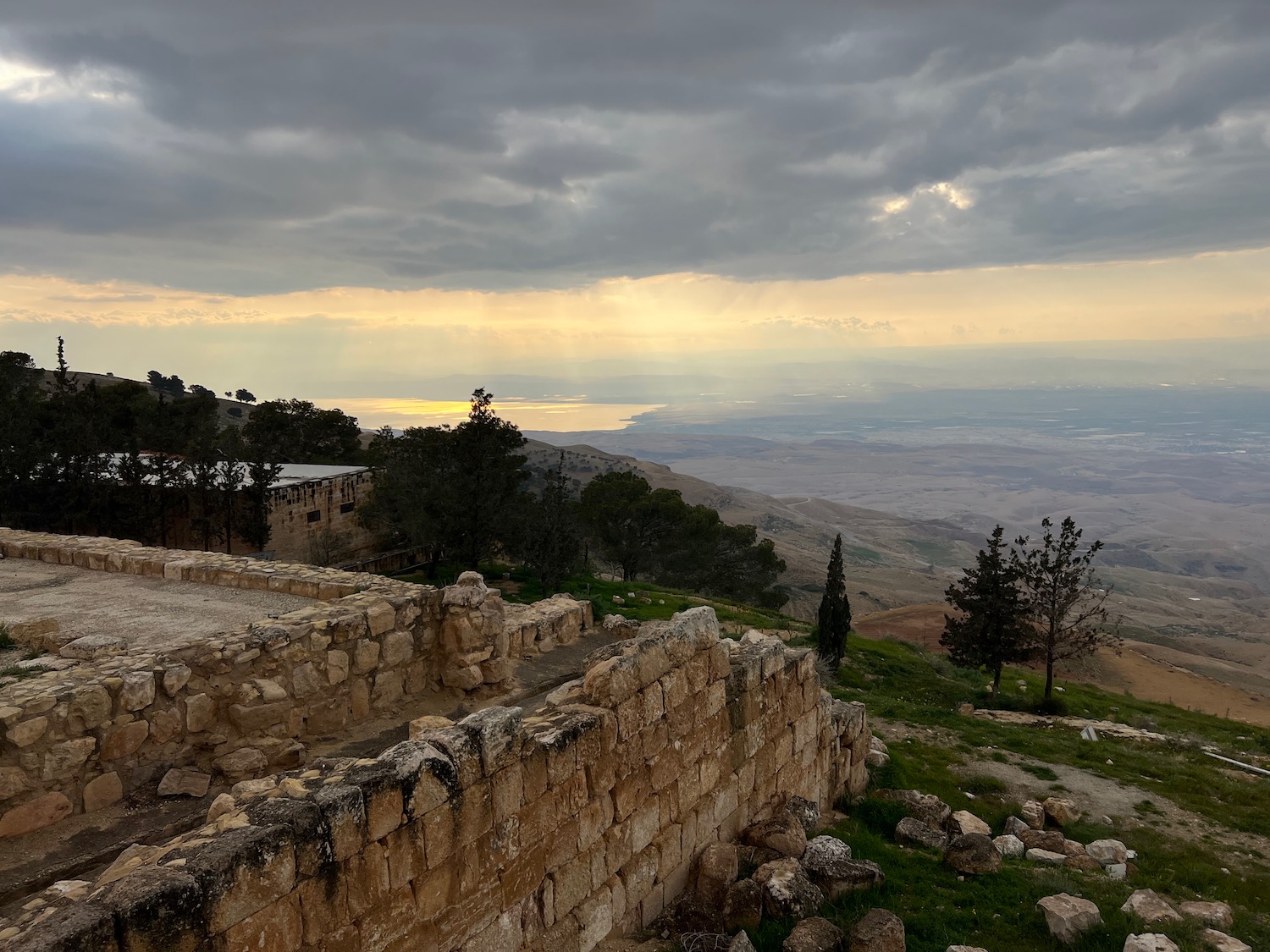 a stone wall with trees and a valley in the background