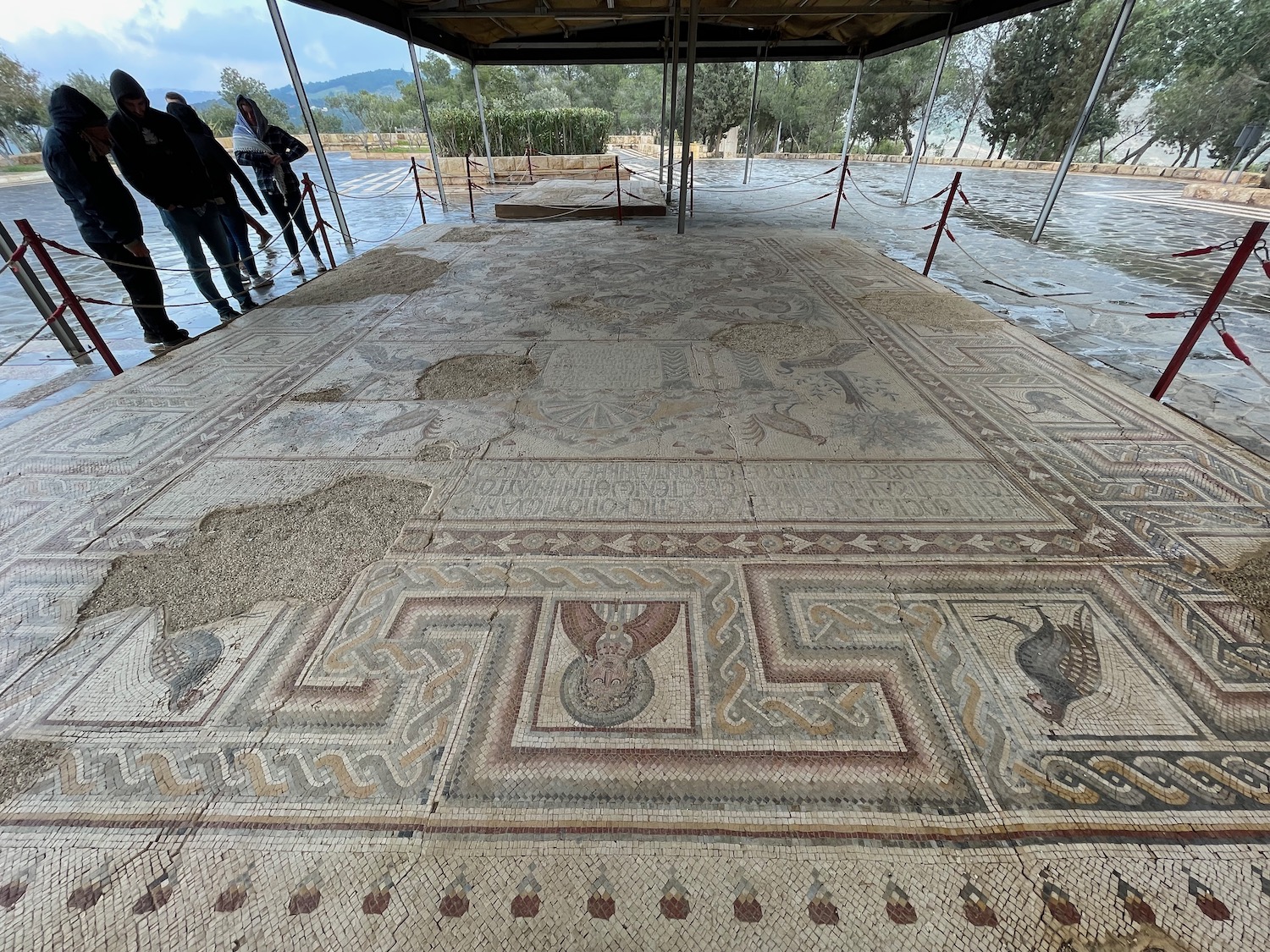 a group of people standing under a covered area with a mosaic