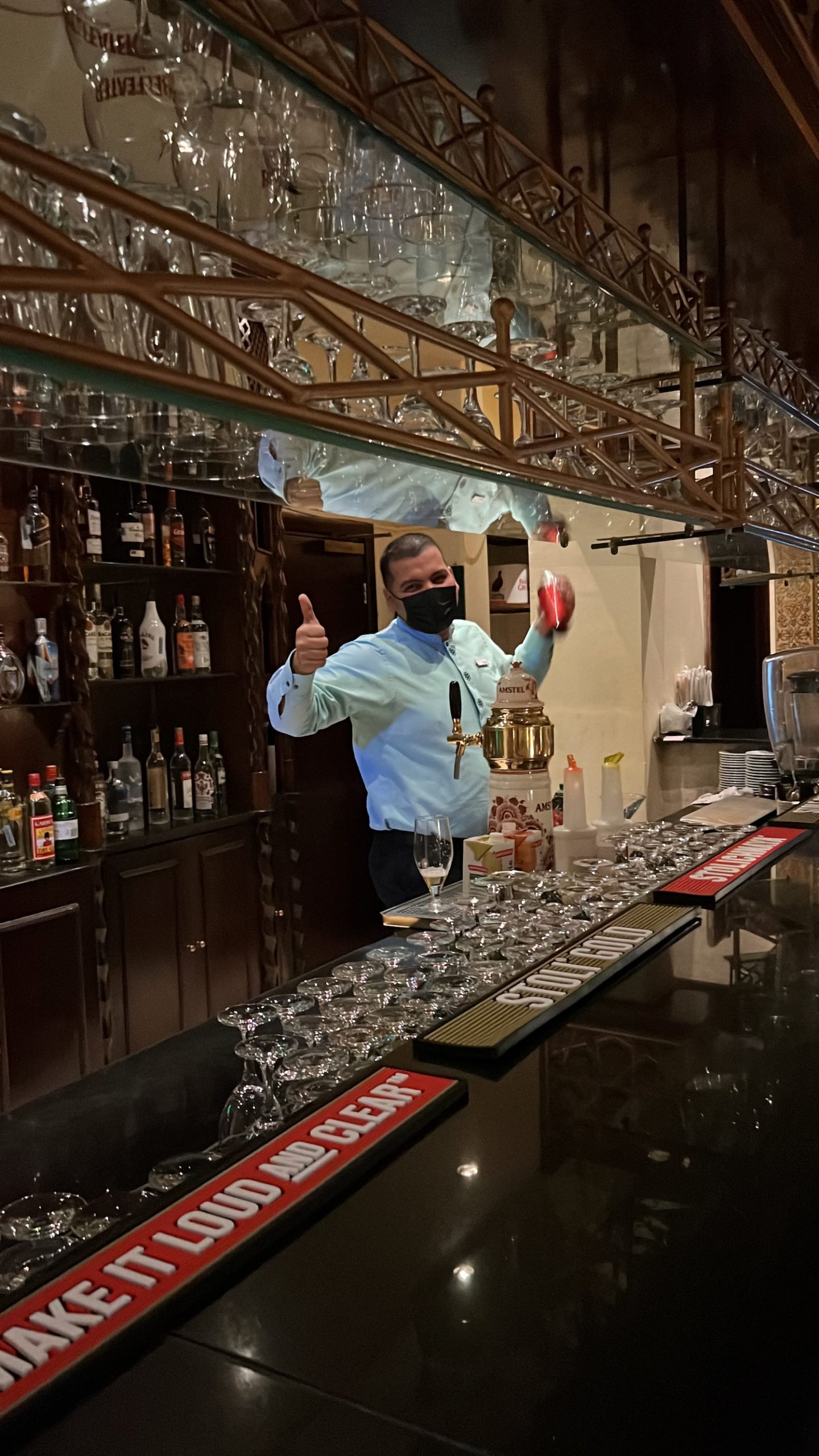 a man wearing a face mask standing behind a bar