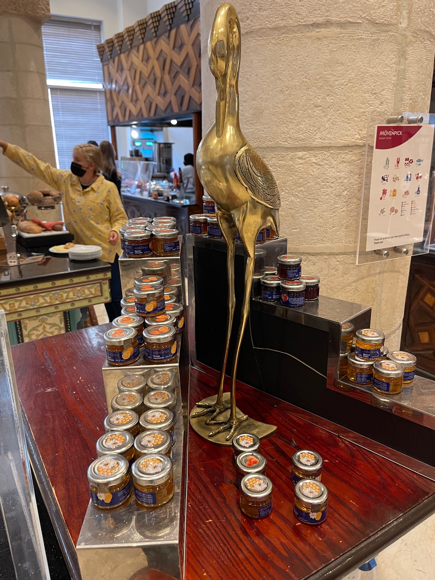 a gold statue of a bird on a table with jars of jam