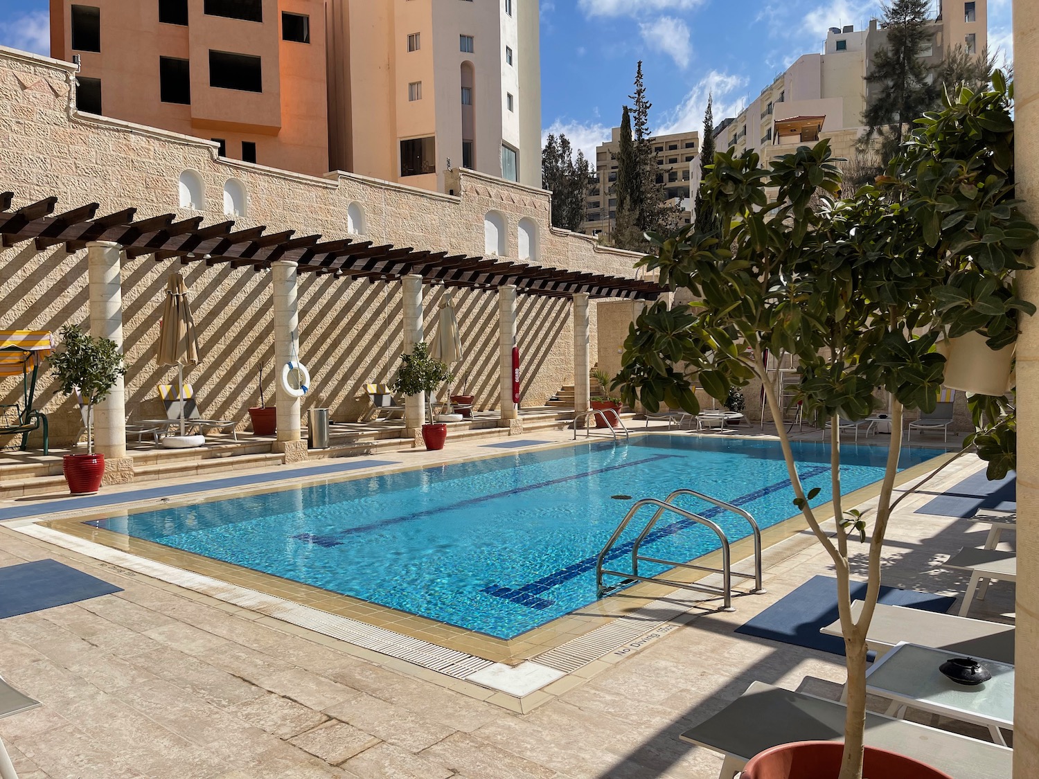 a swimming pool with trees and chairs in front of buildings