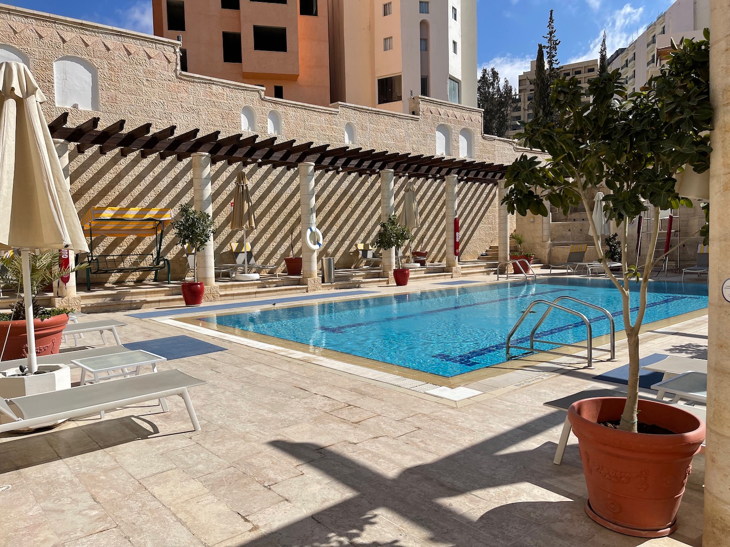 a pool with chairs and a building in the background