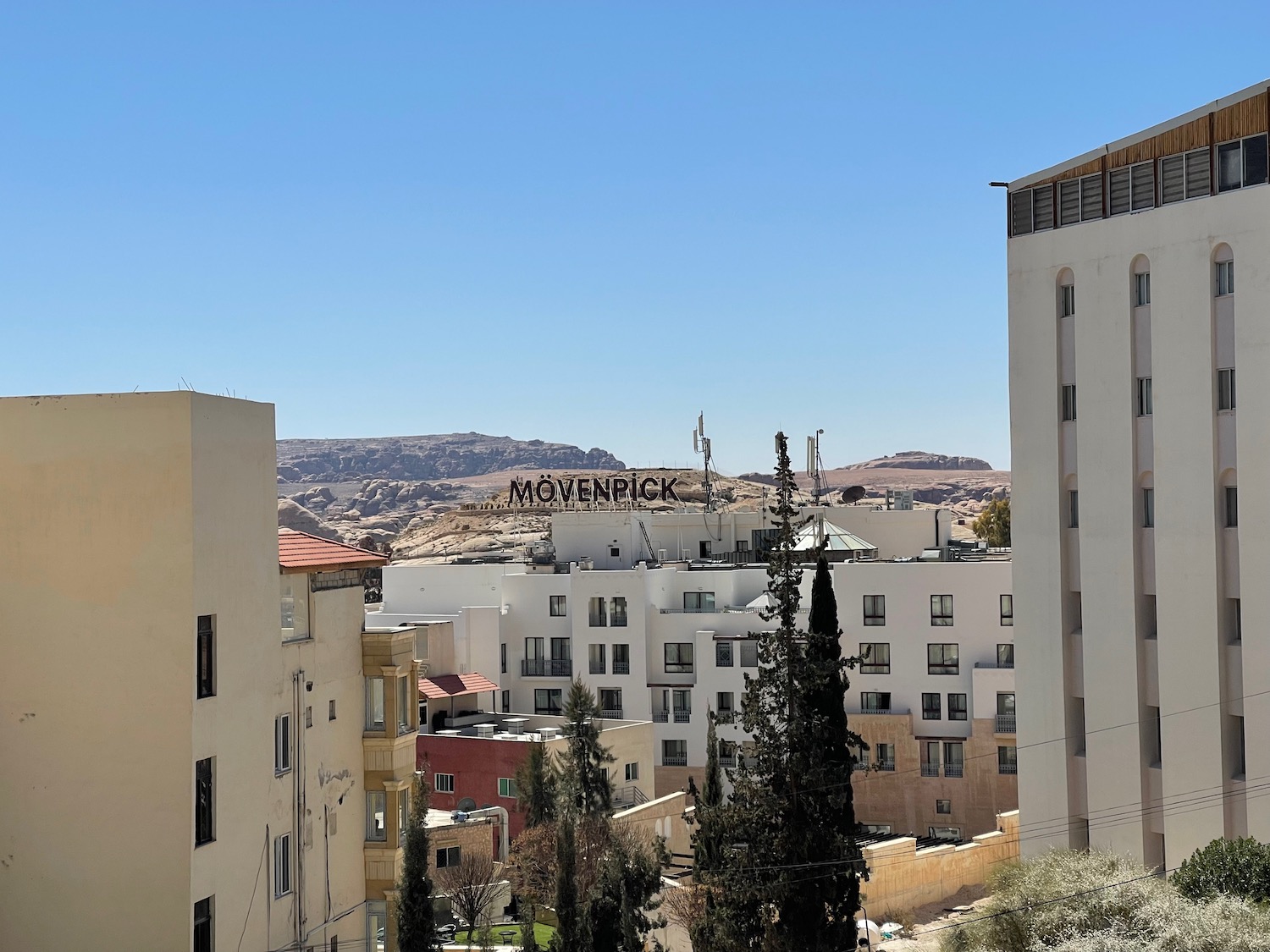 a group of buildings with trees and mountains in the background