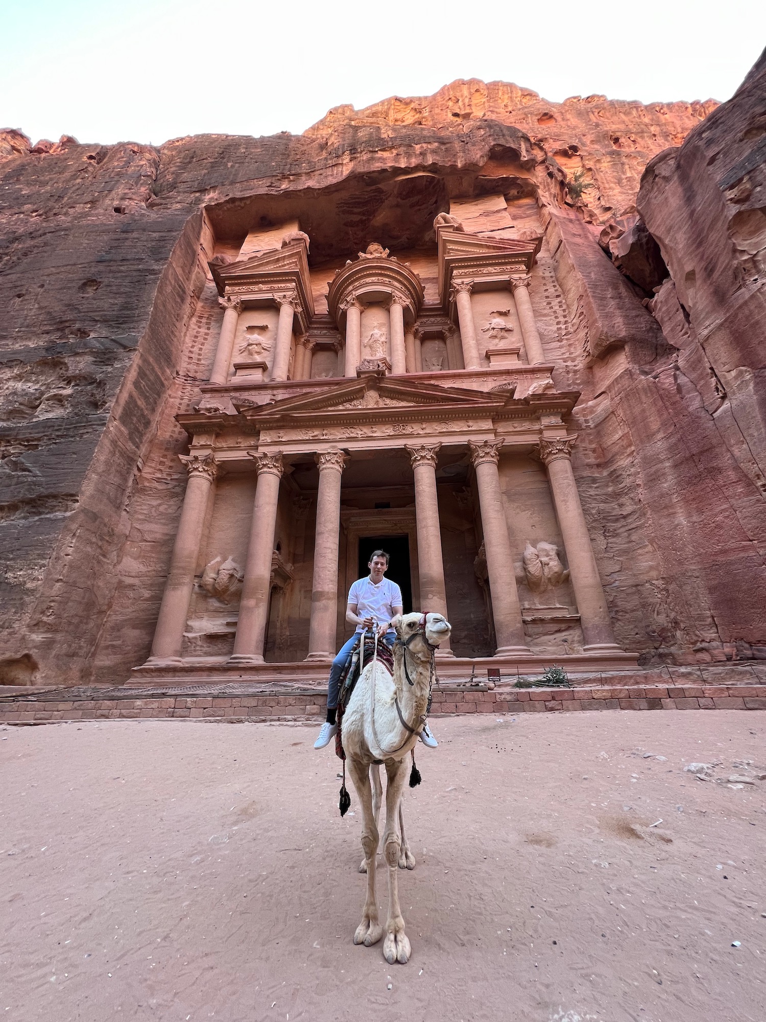 a person riding a camel in front of Petra