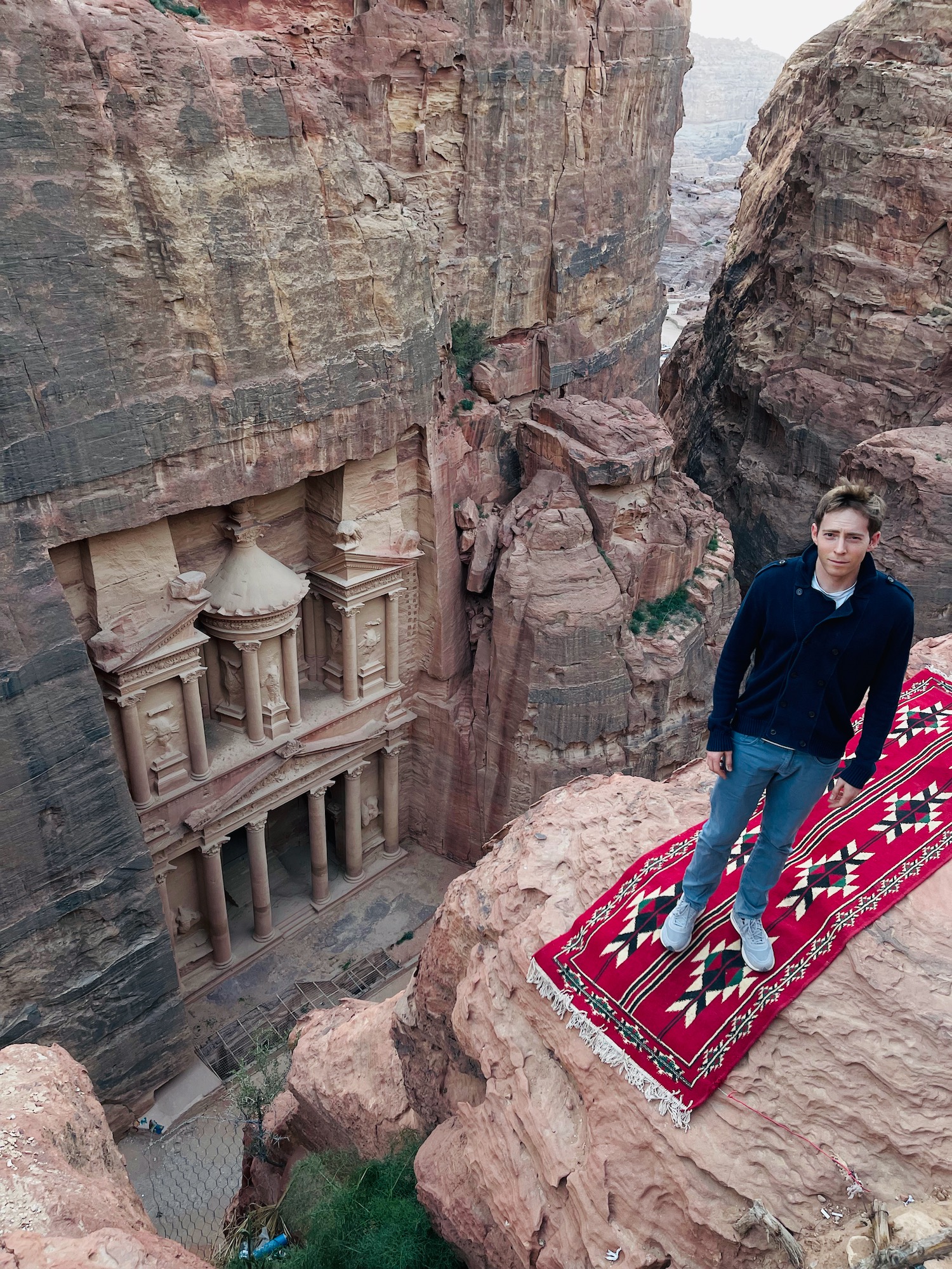 a man standing on a rug on a rock