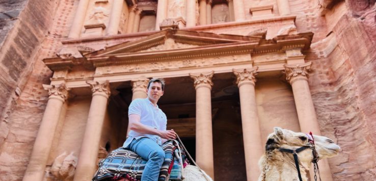 a man riding a camel in front of Petra