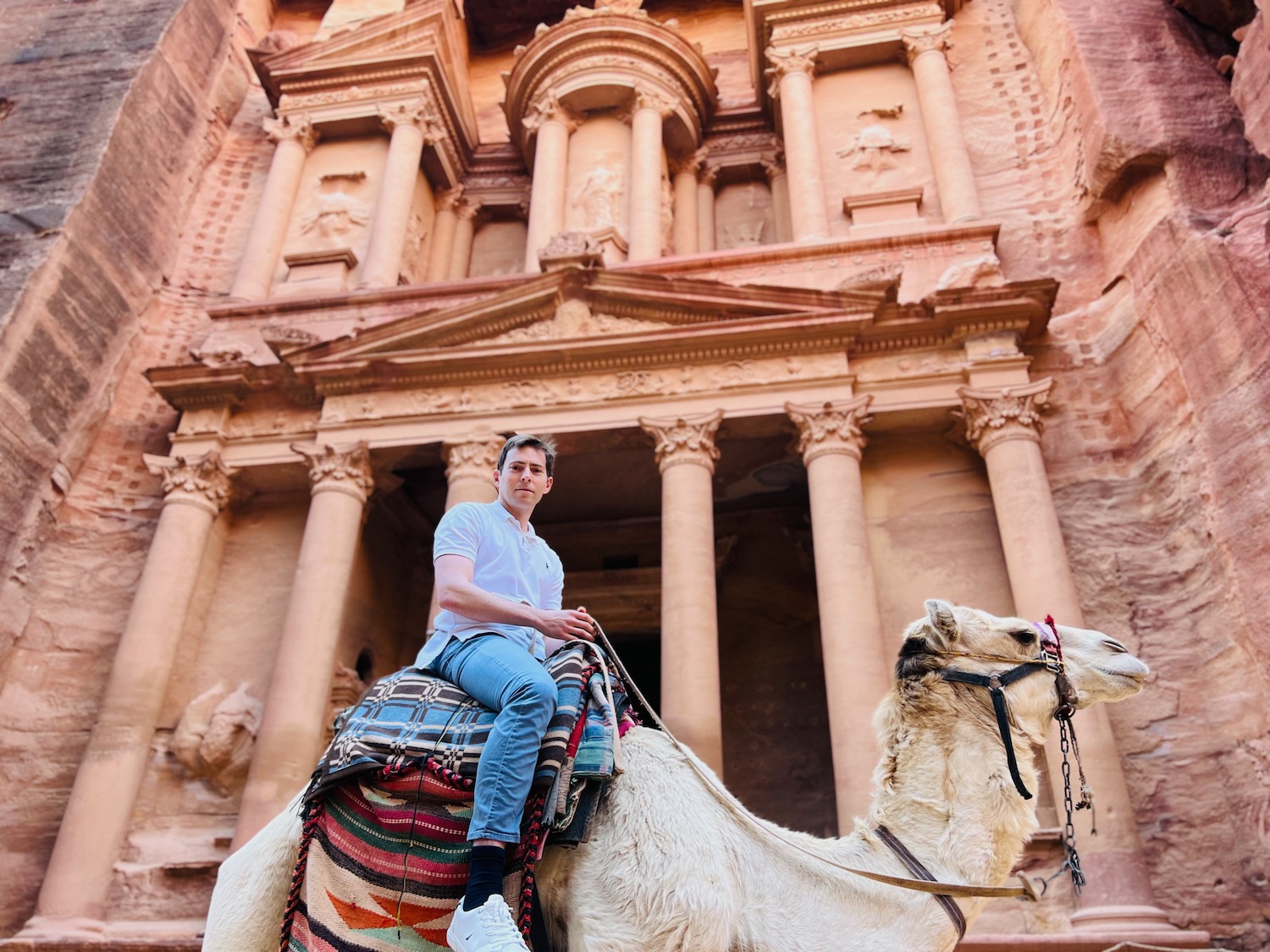 a man riding a camel in front of Petra