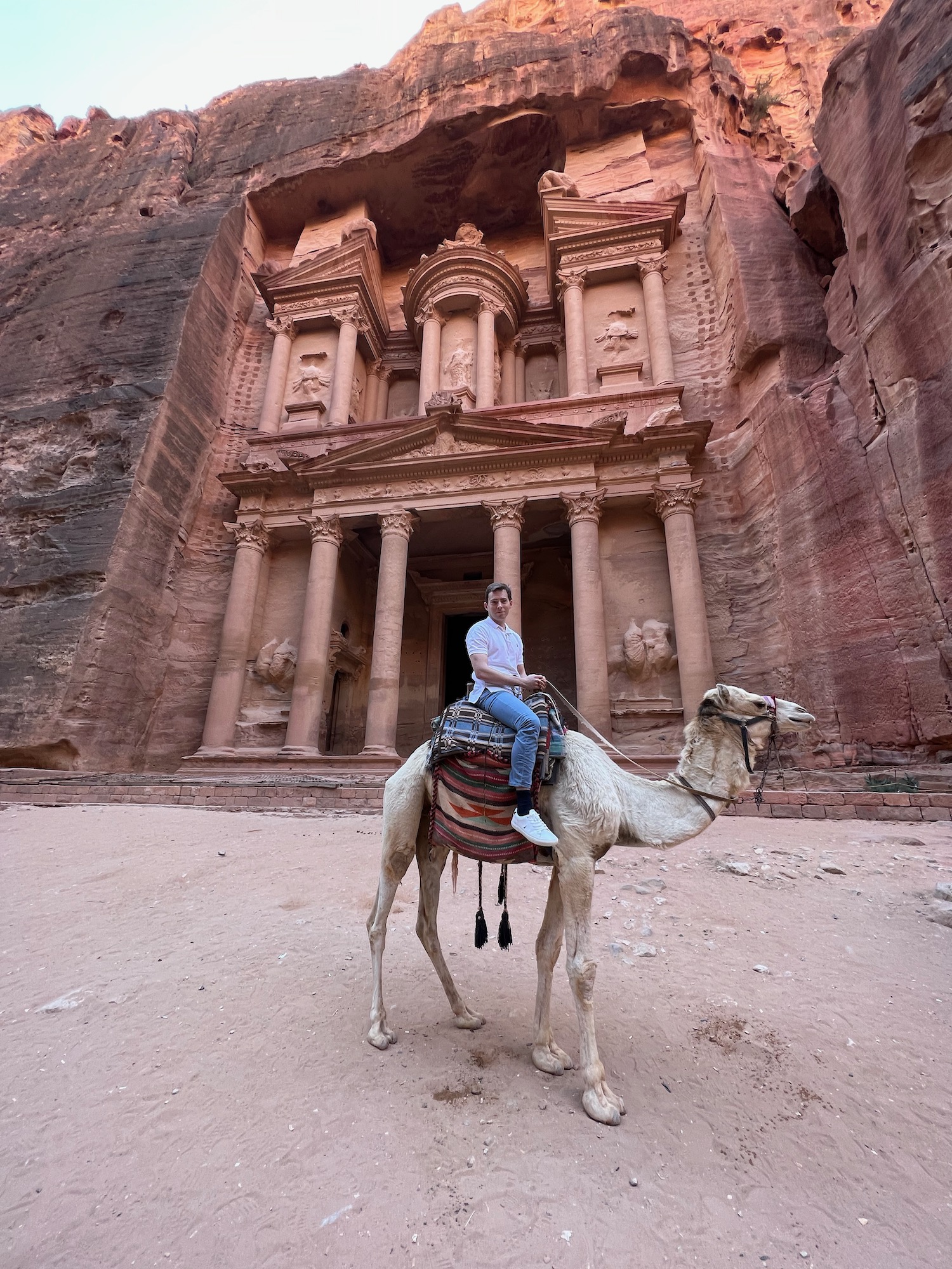 a man riding a camel in front of Petra