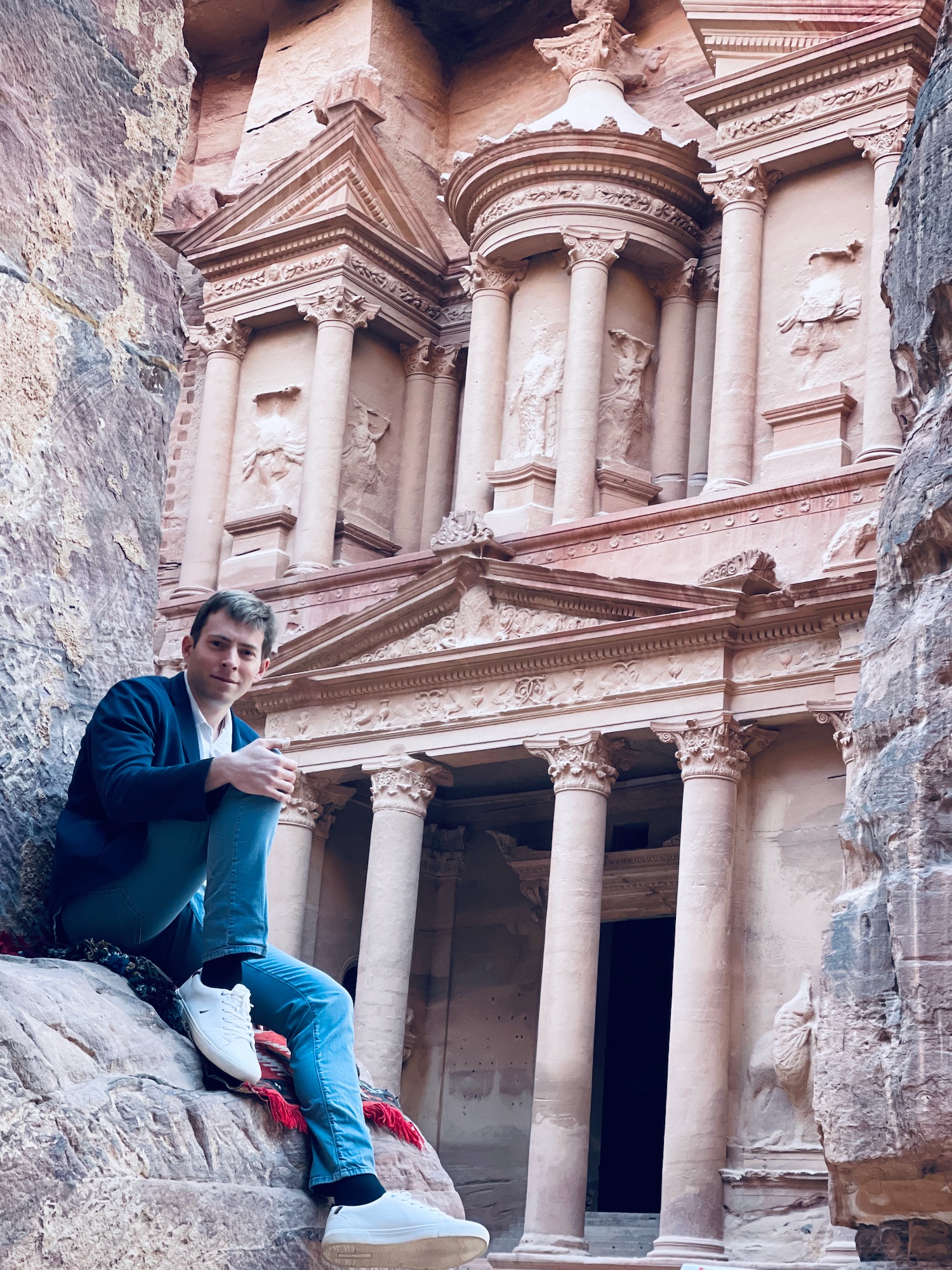 a man sitting on a rock in front of Petra