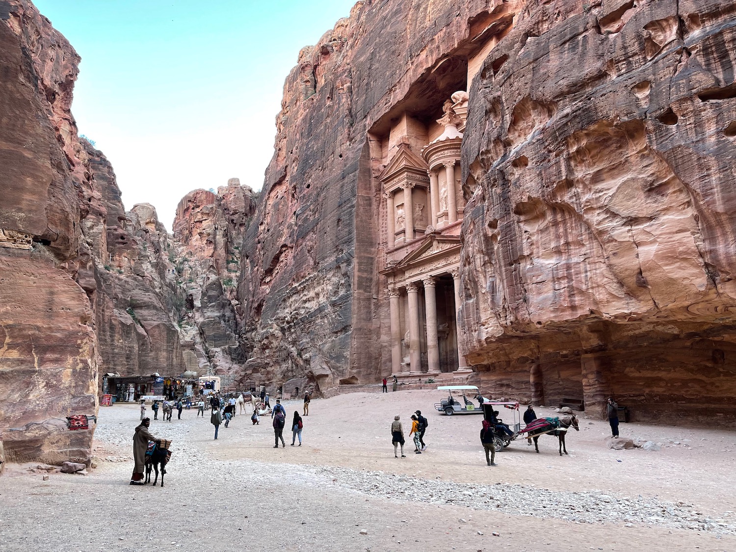 people walking in front of a rock formation with Petra in the background