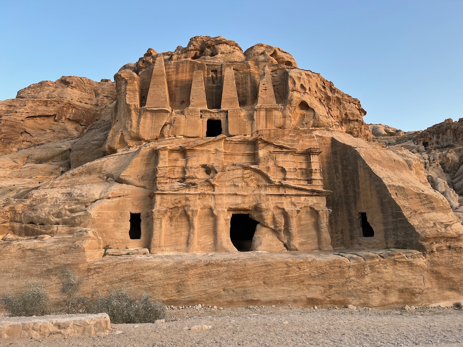 a rock structure with many windows with Petra in the background