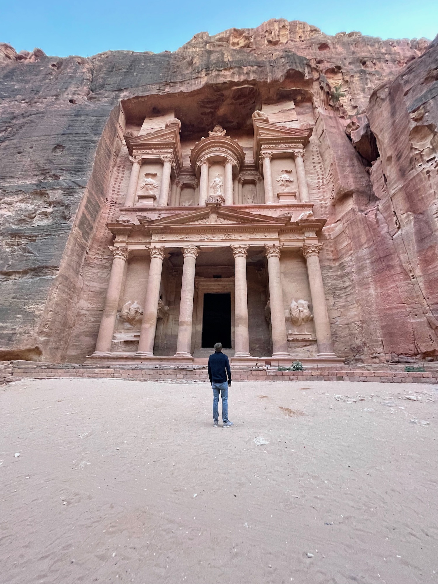 a man standing in front of Petra in a rock formation