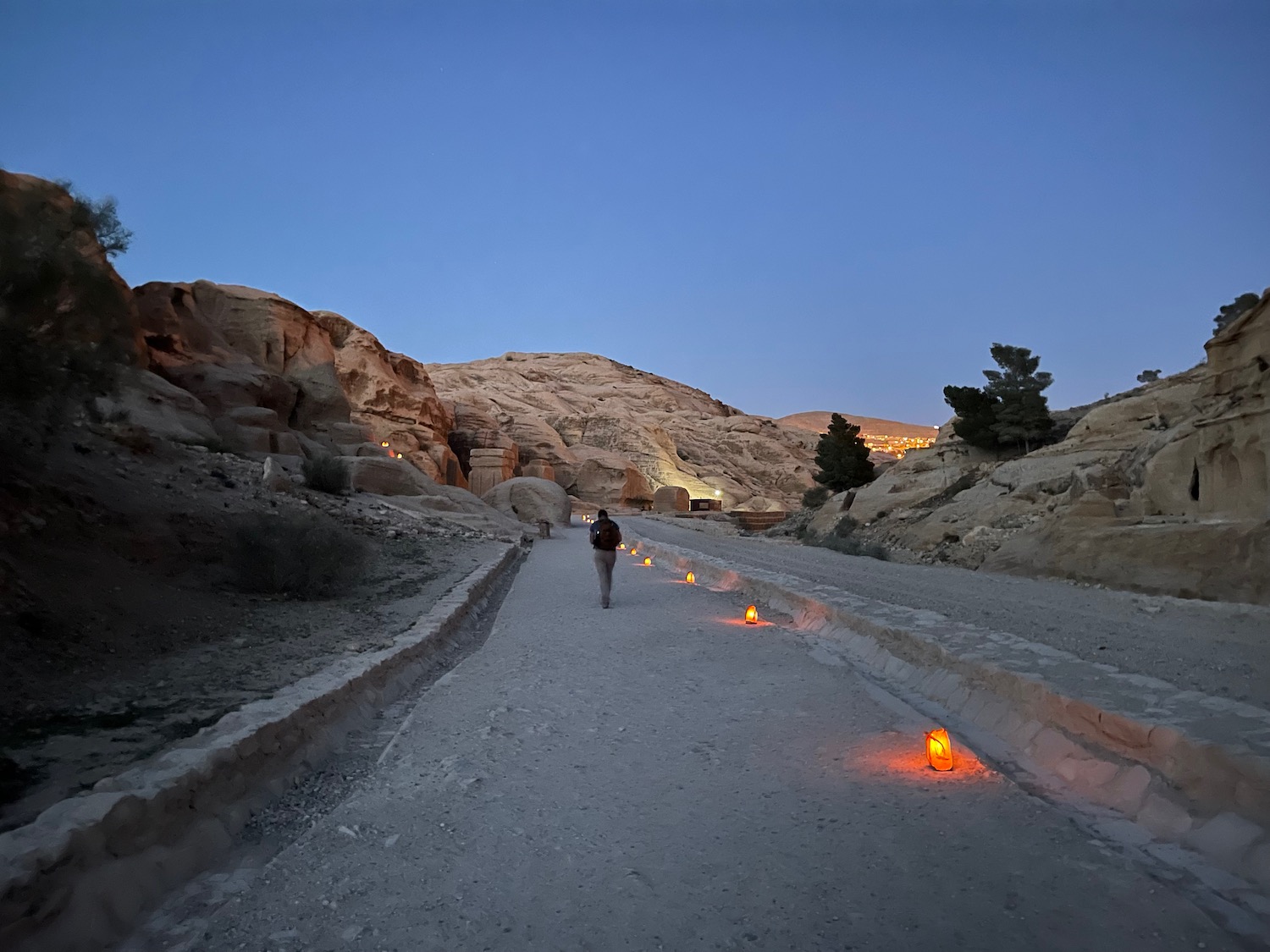 a person walking on a dirt road with lit candles