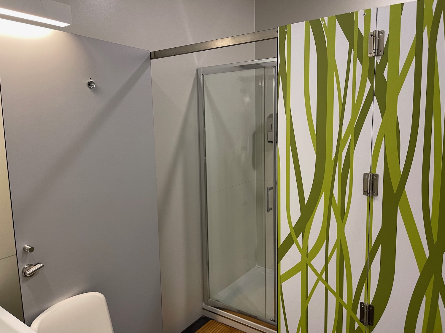 a shower with glass doors and green and white wall