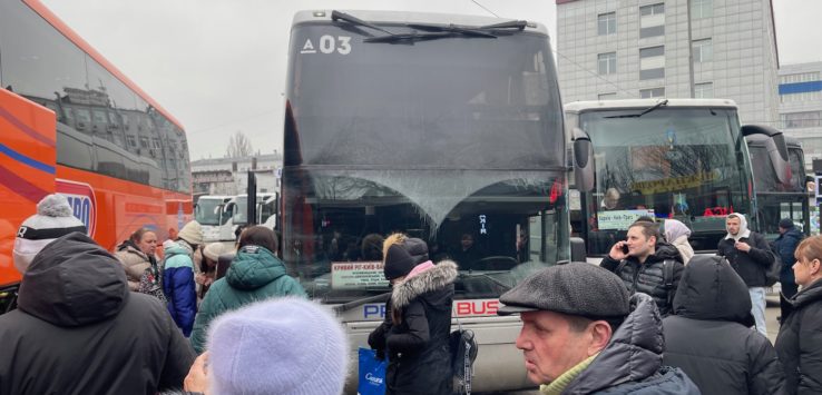 a group of people standing in front of a bus