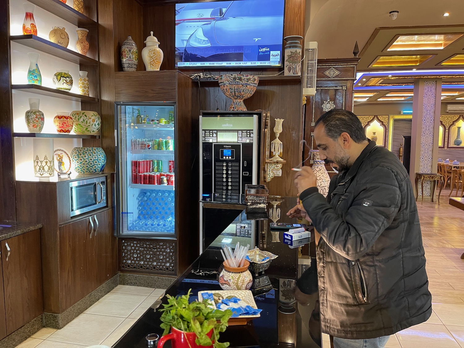 a man standing in a room with a drink machine and a television