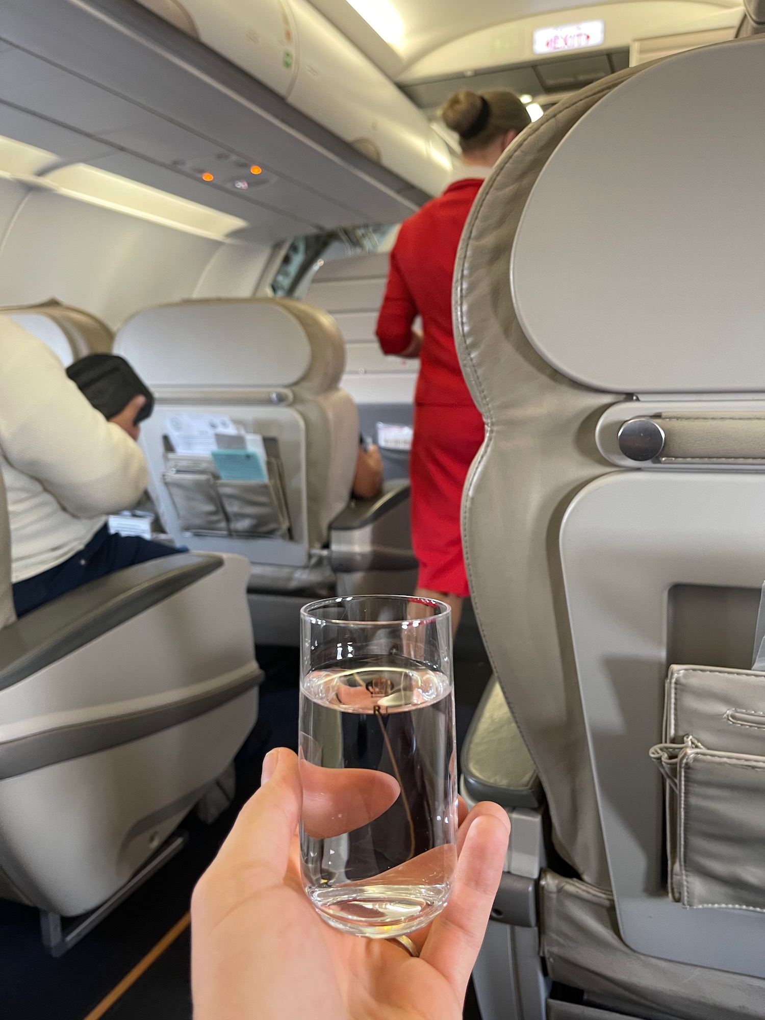 a hand holding a glass of water in an airplane