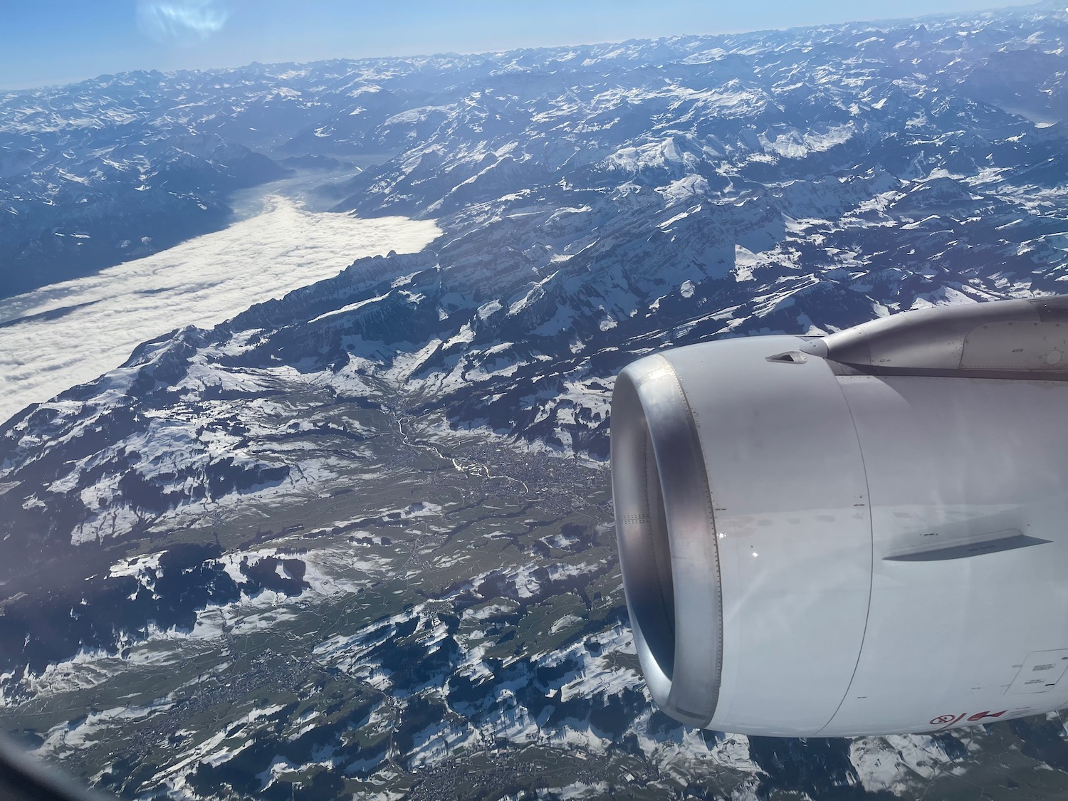 an airplane wing and engine above snowy mountains