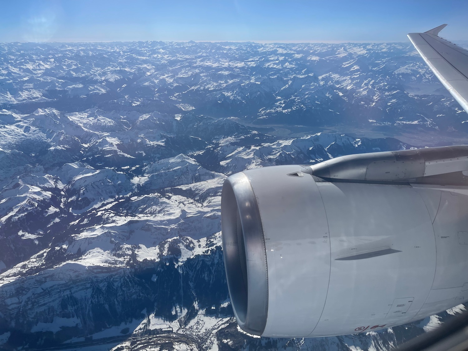 an airplane wing and engine above snow covered mountains