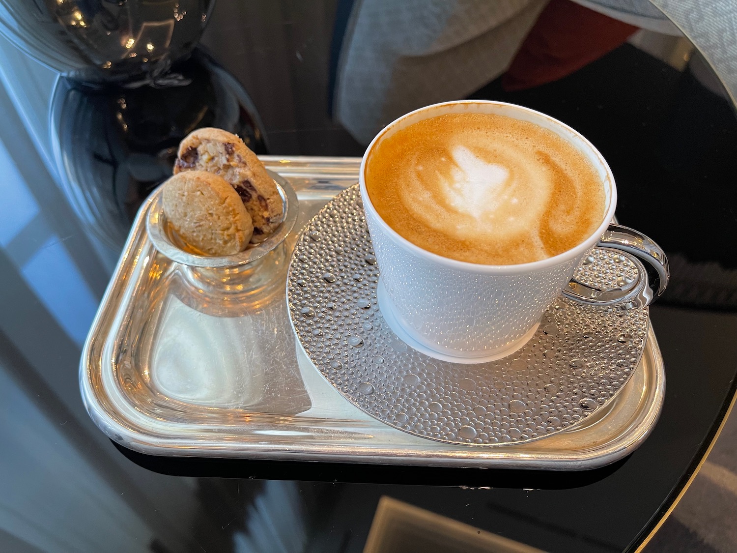 a cup of coffee and a cookie on a tray