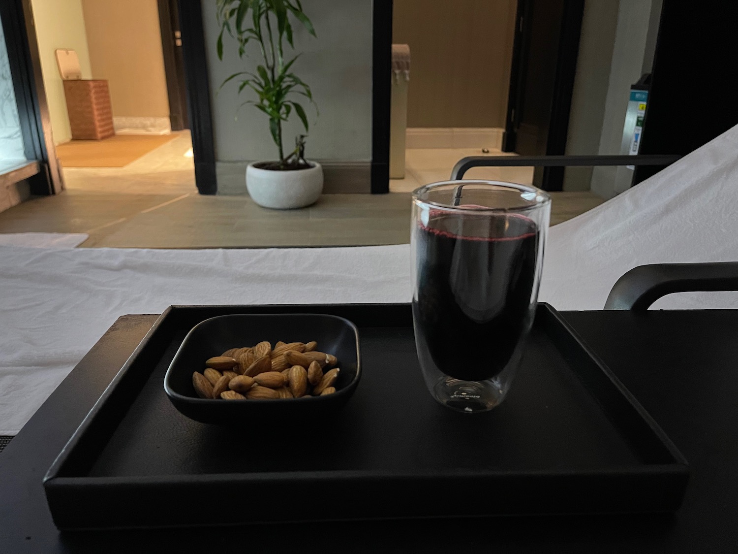 a tray with a bowl of nuts and a glass of liquid on it