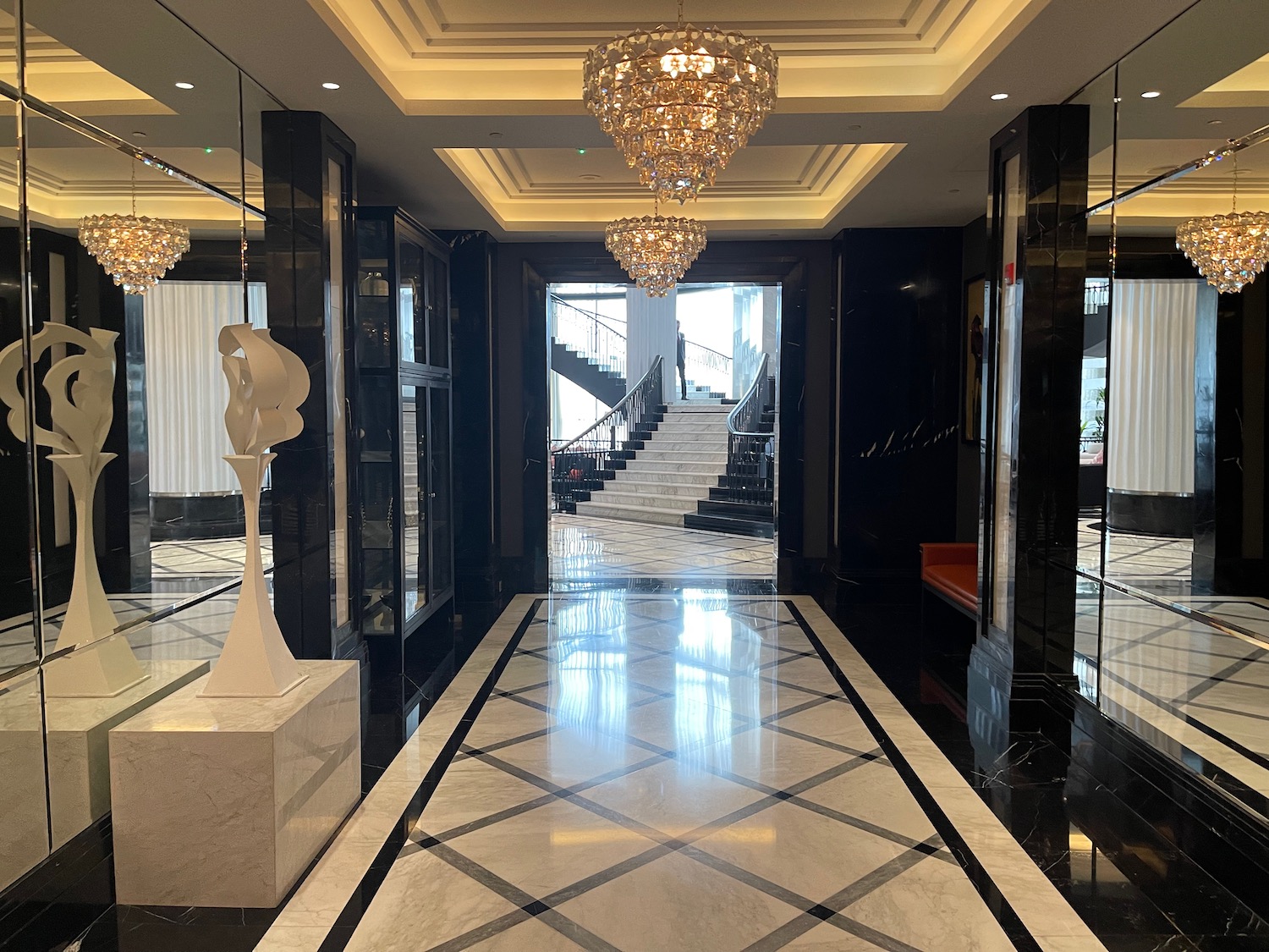 a hallway with chandeliers and stairs