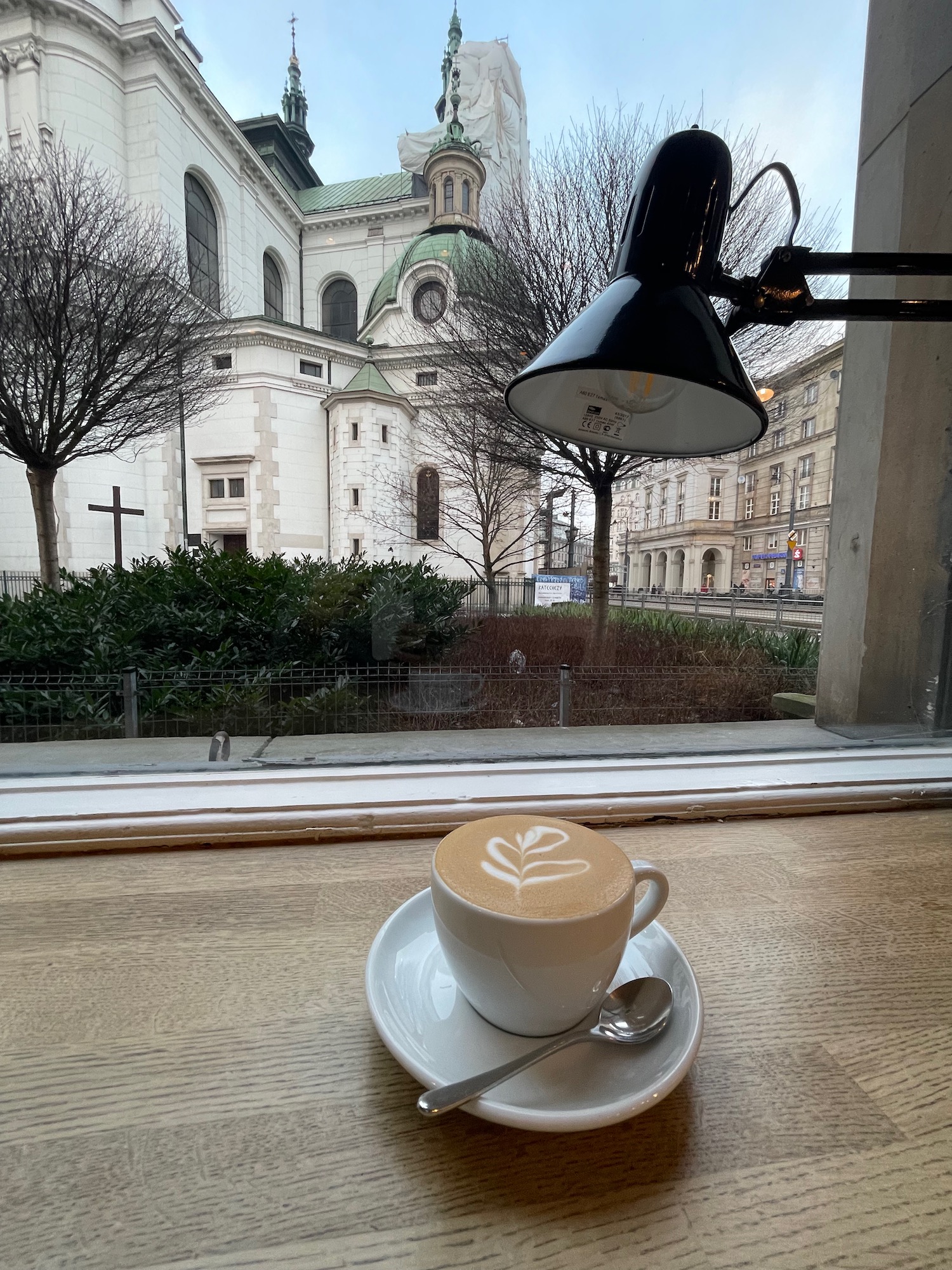 a cup of coffee on a table with a white building in the background