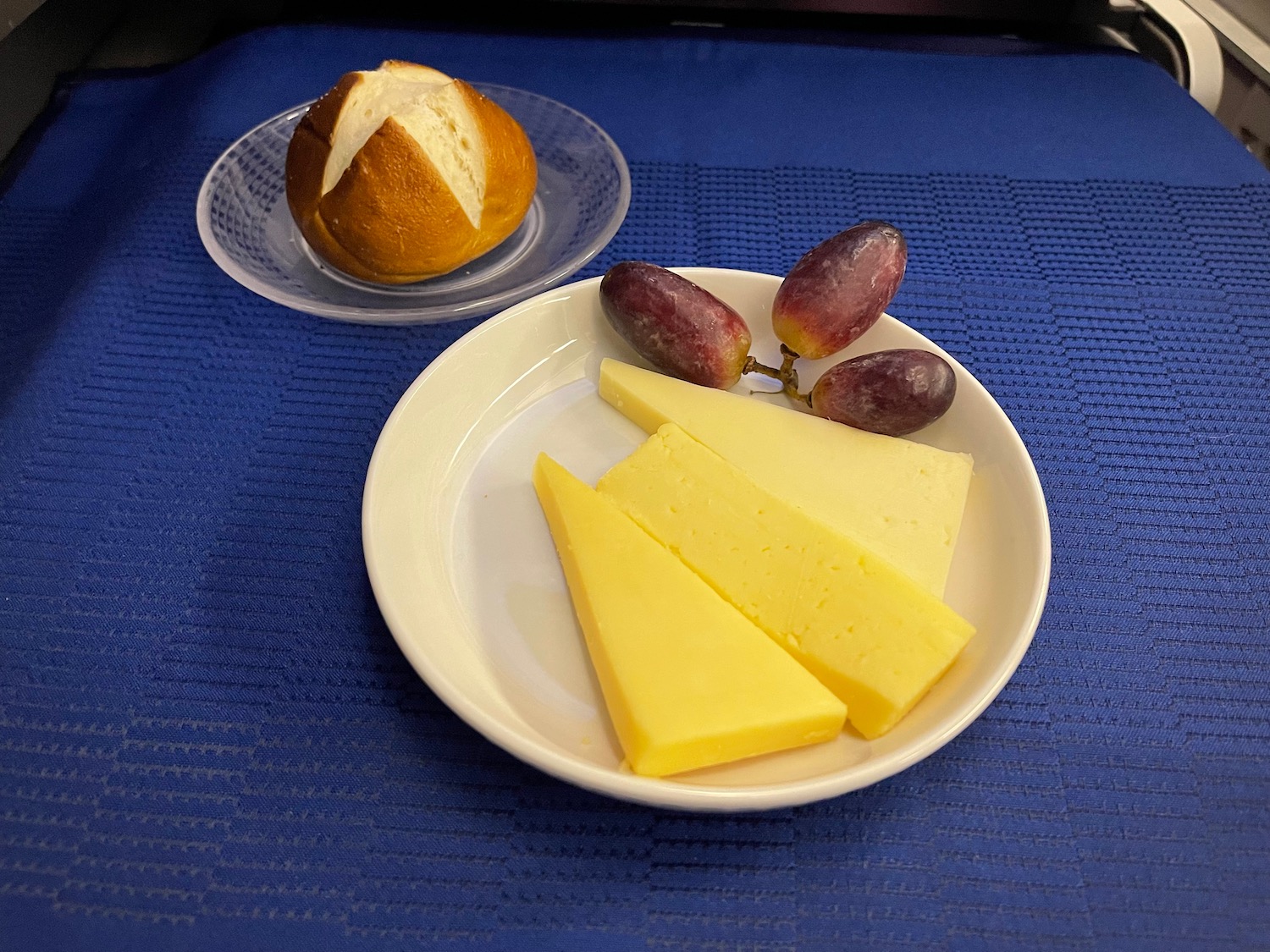 a plate of cheese and grapes on a blue surface