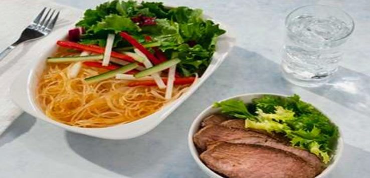 a plate of noodles and vegetables in a bowl of meat