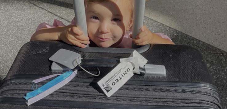 a child peeking through bars of luggage