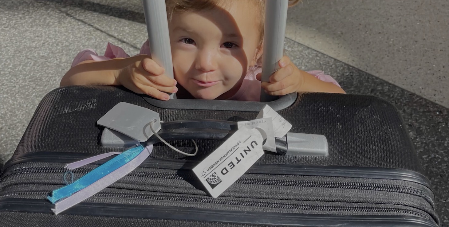 a child peeking through bars of luggage
