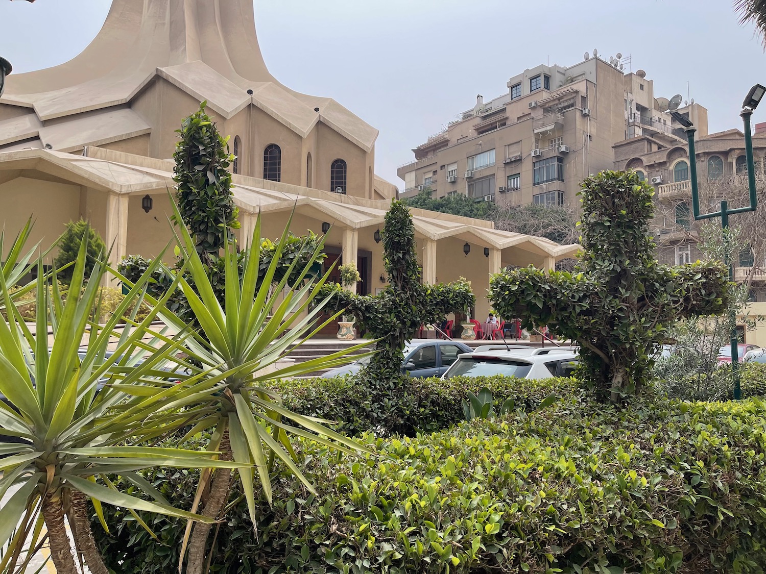 a building with a tall tower and bushes