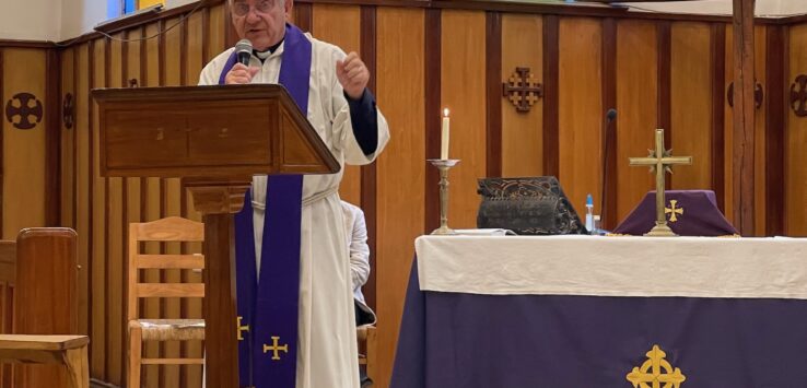 a man in a white robe standing at a podium