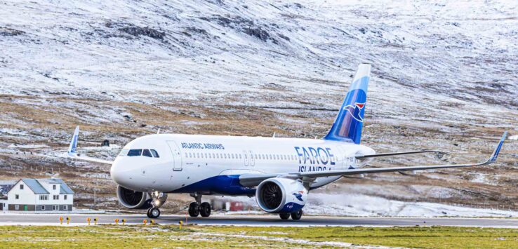 a plane on a runway with snow covered mountains in the background