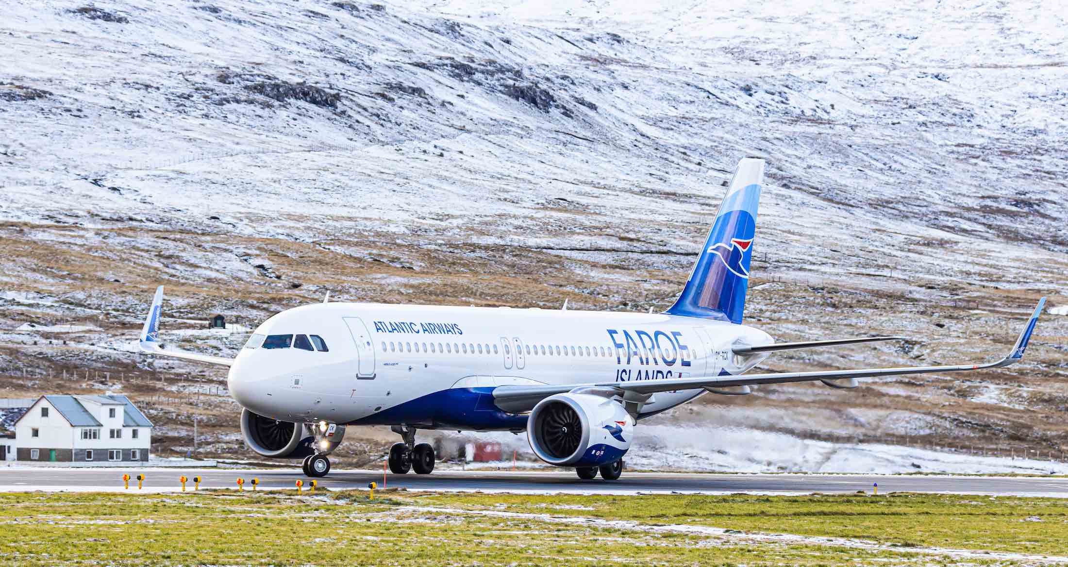 a plane on a runway with snow covered mountains in the background