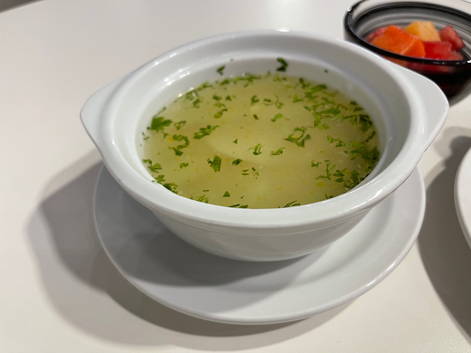 a bowl of soup with parsley on a white plate