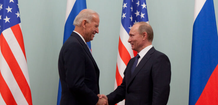 two men shaking hands in front of flags
