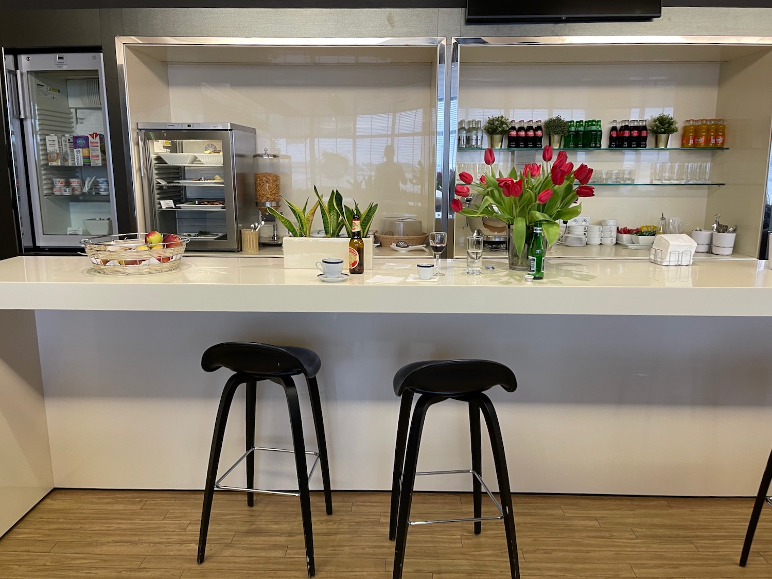 a white bar with black stools and a vase of flowers