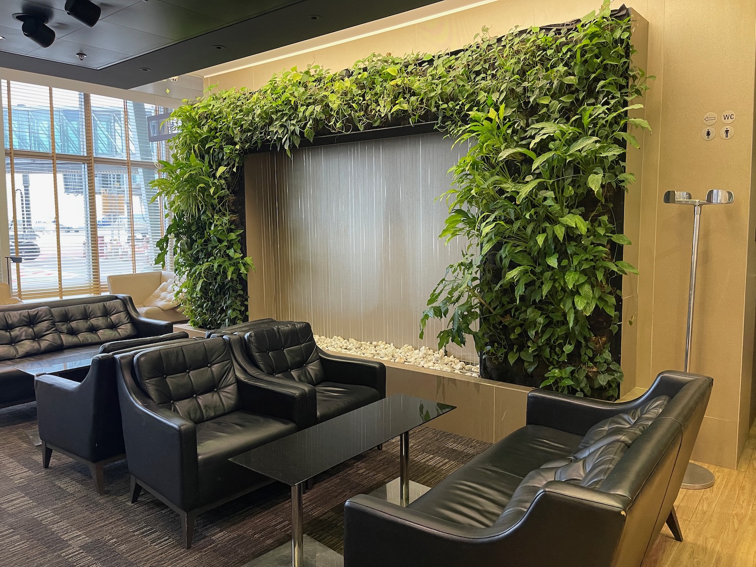 a room with a wall of plants and chairs