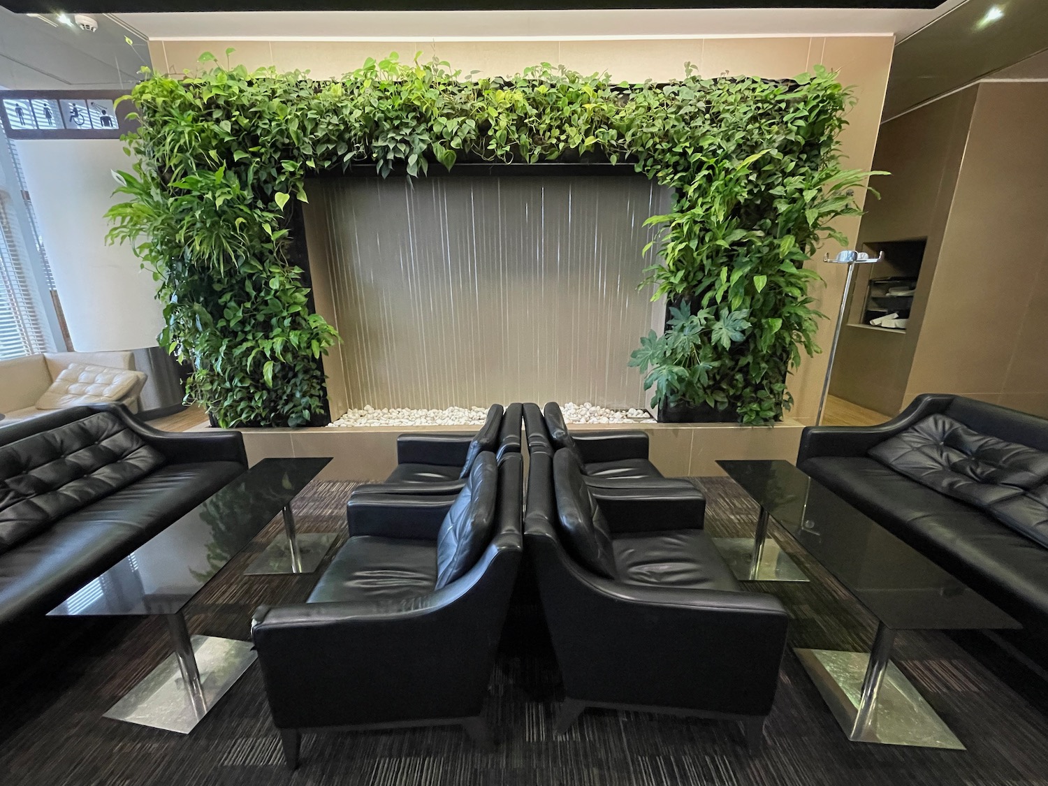 a room with black chairs and a wall covered in plants