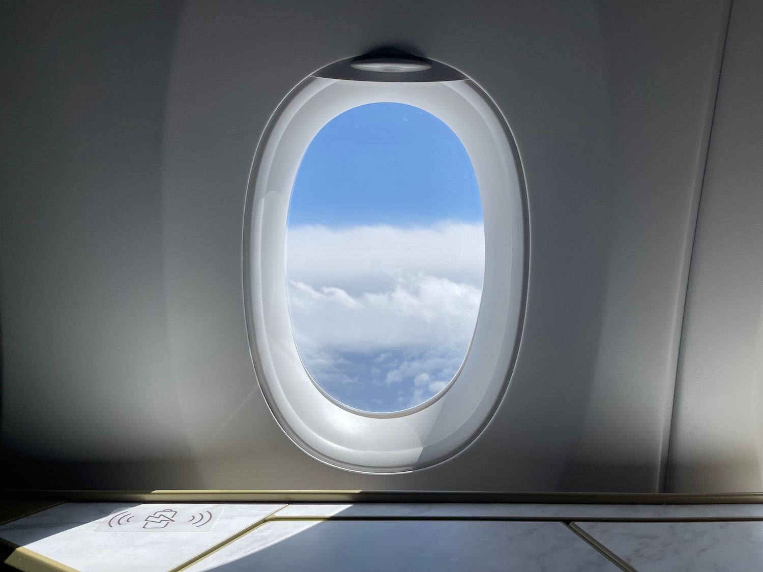 a window with a view of clouds and blue sky