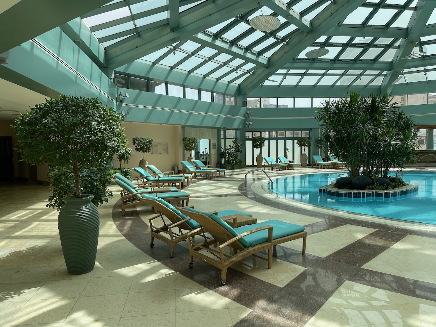 a pool with chairs and trees in a room