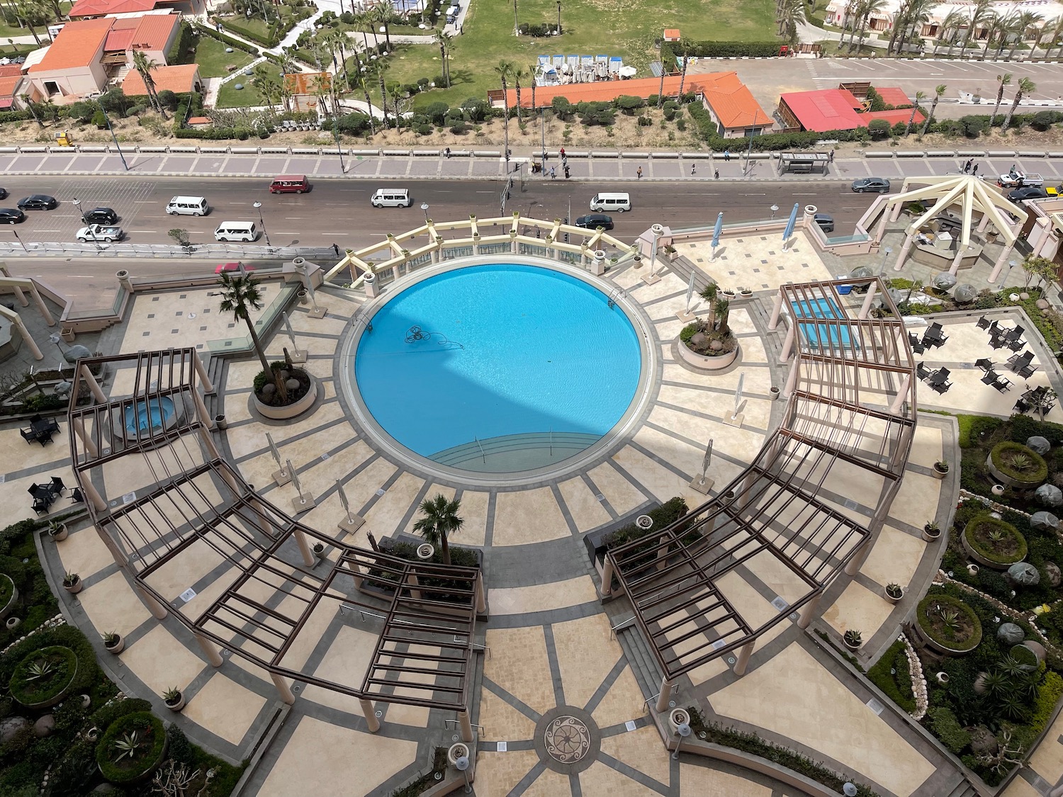 a pool with a circular structure and a road with cars and buildings