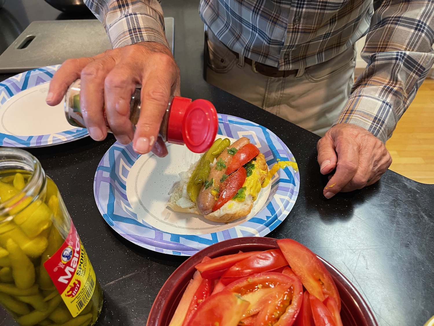a person pouring seasoning on a hot dog