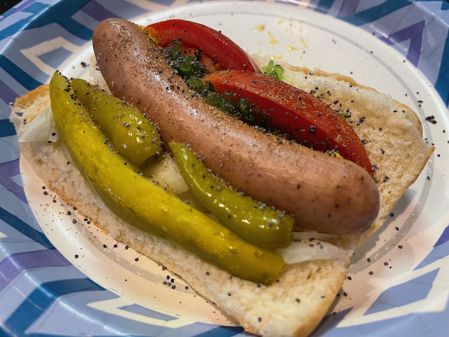 a hot dog sandwich with tomatoes and pickles on a plate