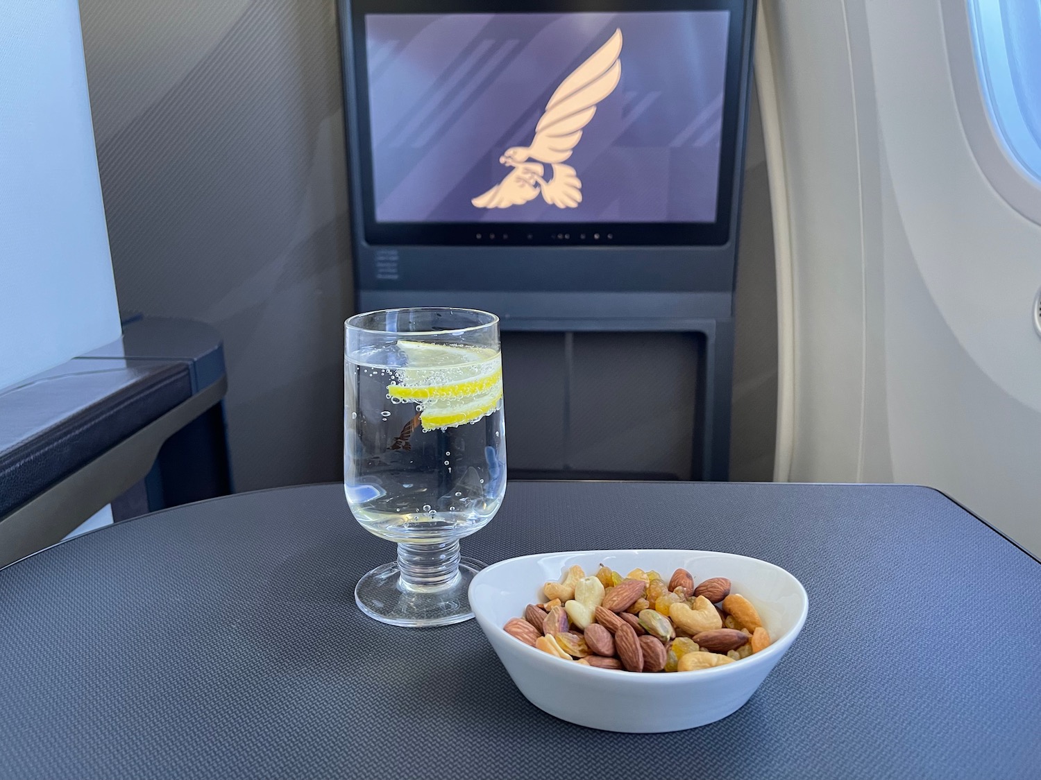 a bowl of nuts and a glass of water on a table